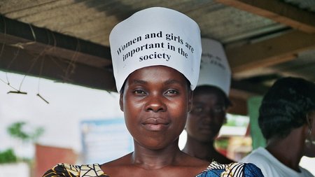 A woman wearing a print-out of the slogan “Women and girls are important in the society” which has been attached onto a headband.